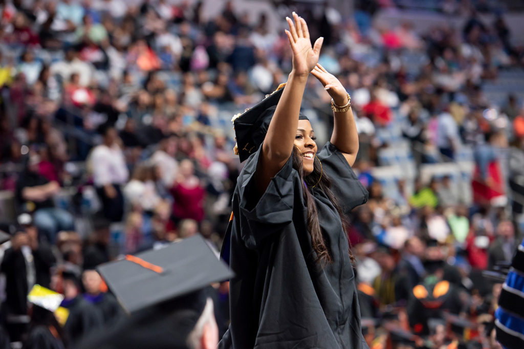 A female graduate with her hands in the air celebrating the 2018 Commencement ceremony