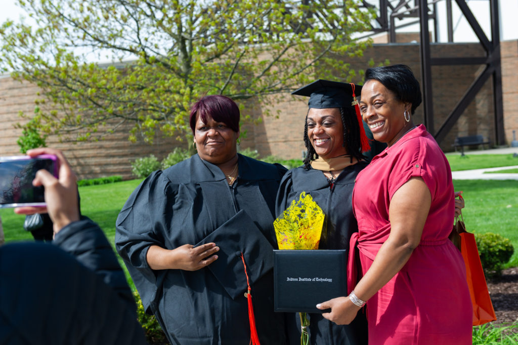 Graduates posing with their families outside after the commencement ceremony