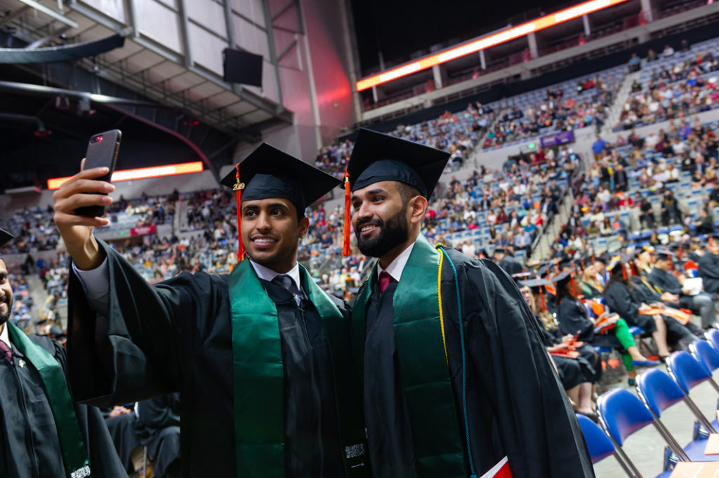 Two international students posing together for a photo during the 2019 commencement ceremony