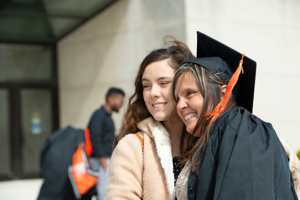 Graduate posing with her daughter outside after the commencement ceremony