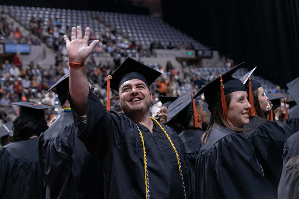 Graduate waving at his friends and family during the commencement ceremony