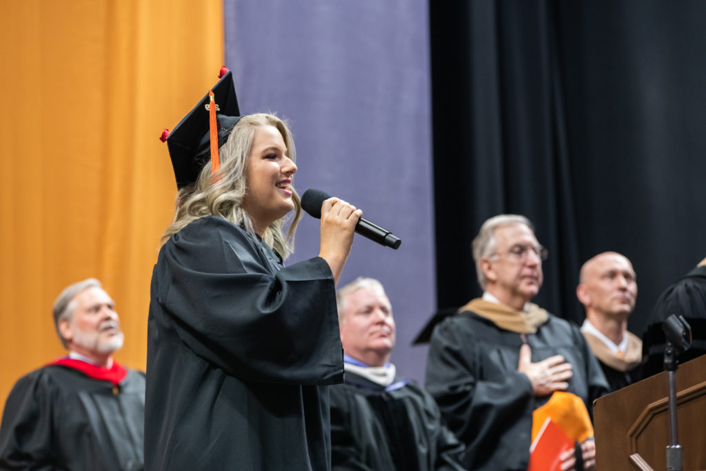 Graduate Kelsey Crilly singing the national anthem during the commencement ceremony