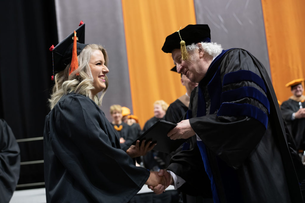 Dr. Evans presenting a degree to graduating Kelsey Crilly during the commencement ceremony