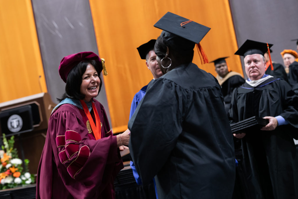 Kathleen Watland celebrating with a student on stage during the commencement ceremony