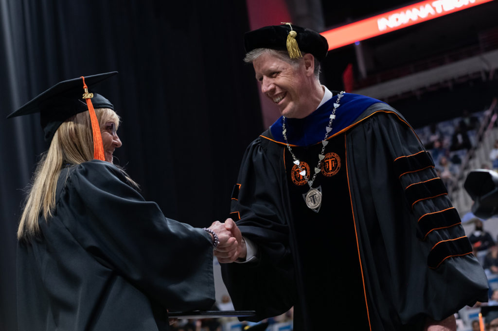 President Einolf shaking the hand of a graduate walking across stage