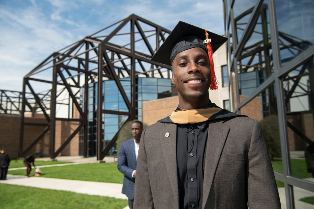 A graduating student posing outside after commencement