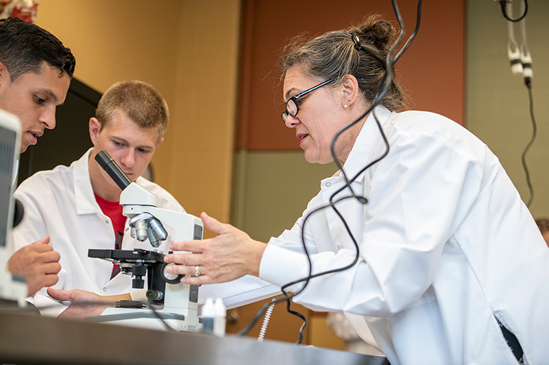 Dr. Julie Davis Good demonstrating how to use a microscope with a student in Bio Lab