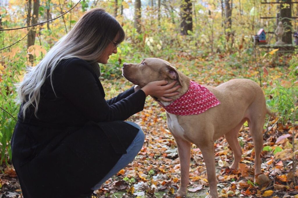 Madison Bouwer's dog, Cash, a pitbull, poses with Madison in the woods