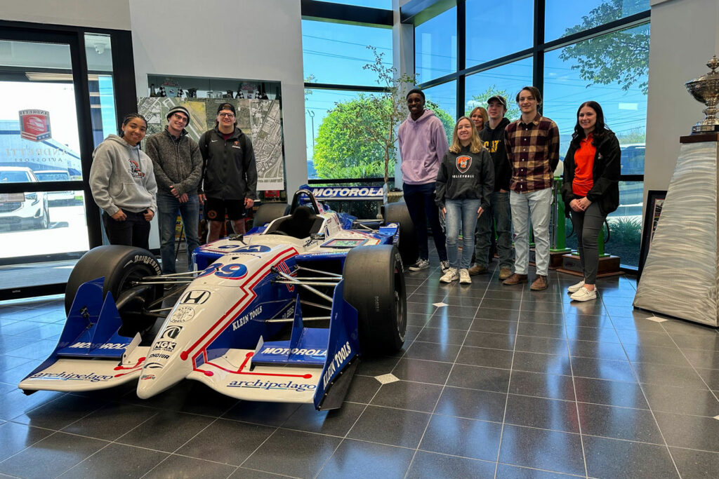 Students posing with an Indy car