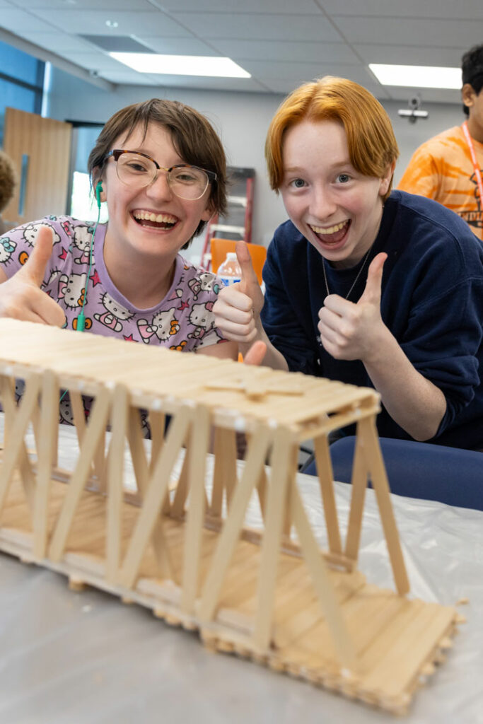 Students posing with their popsicle stick bridge