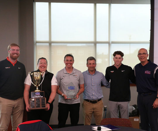 Indiana Tech Athletics staff holding the Fred Smith Commissioner Cup